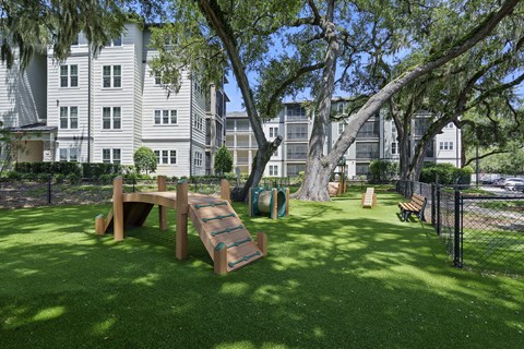 A playground with a slide and a wooden bench is in the foreground of a grassy area.