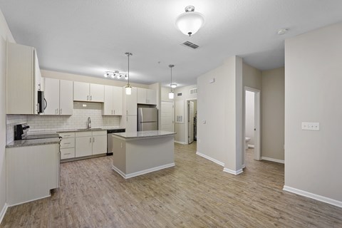 A kitchen with white cabinets and a wooden floor.
