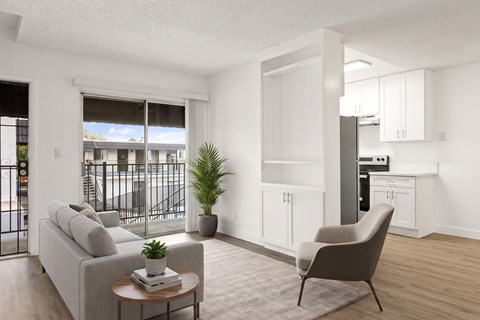 A living room with a grey couch, a brown armchair, a coffee table, and a potted plant.