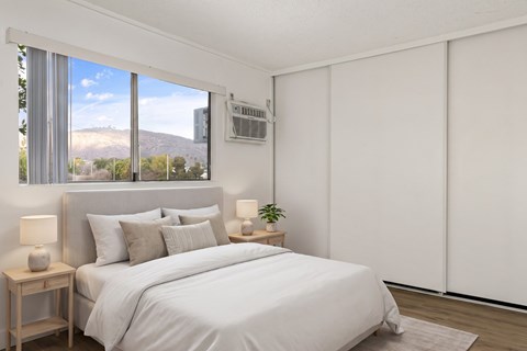 A bedroom with a large bed and a window overlooking a mountain.