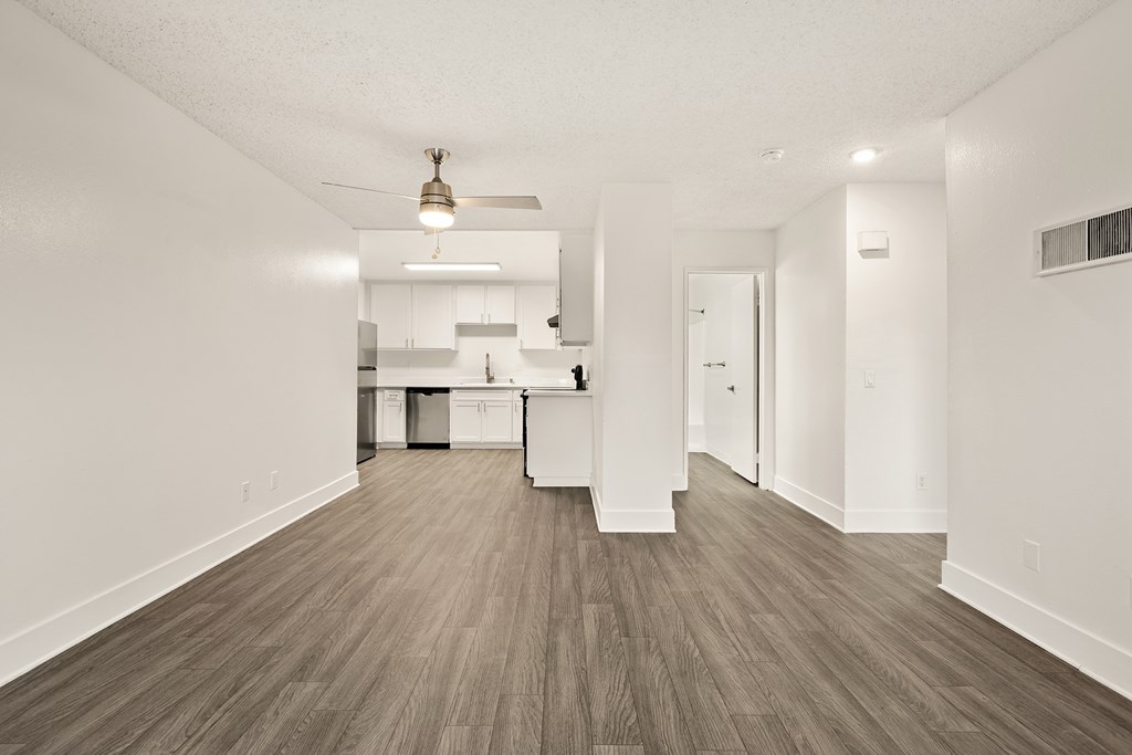 A kitchen with white cabinets and a wooden floor.
