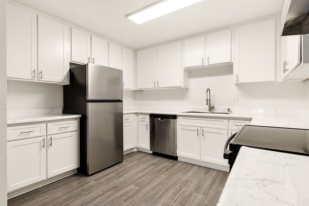A kitchen with white cabinets and a black refrigerator.