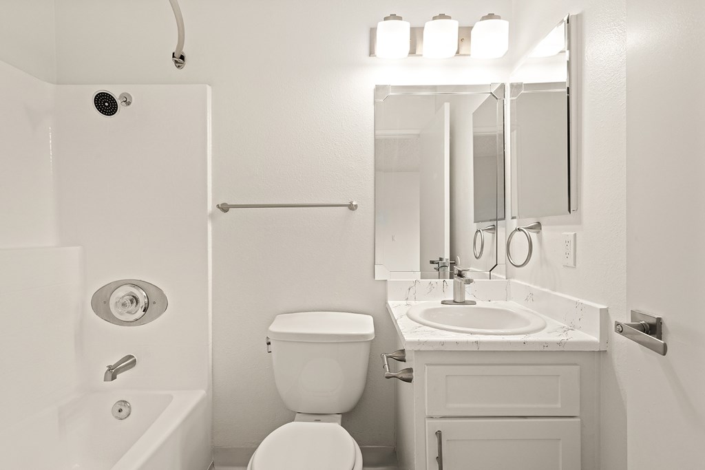 A white bathroom with a toilet, sink, and mirror.