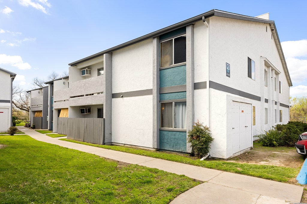 A white building with a grey roof and a blue door.