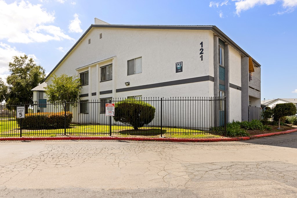 A white building with a black fence and gate in front.