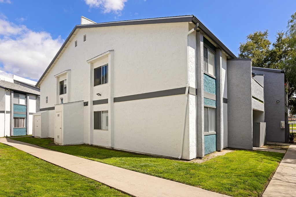 A white building with a grey roof and a green lawn in front.
