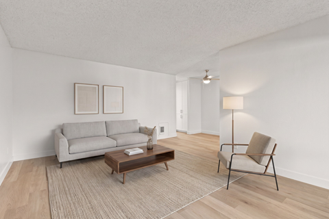 A living room with a grey couch, a brown coffee table, and a chair with a beige cushion.