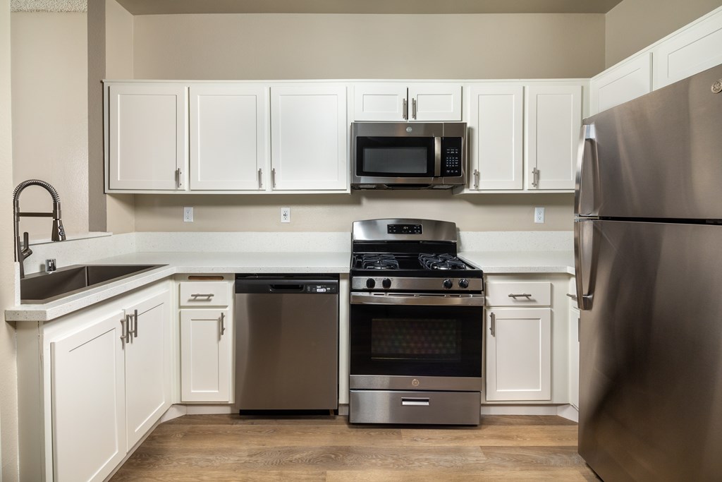 A kitchen with a stainless steel refrigerator, oven, and microwave.