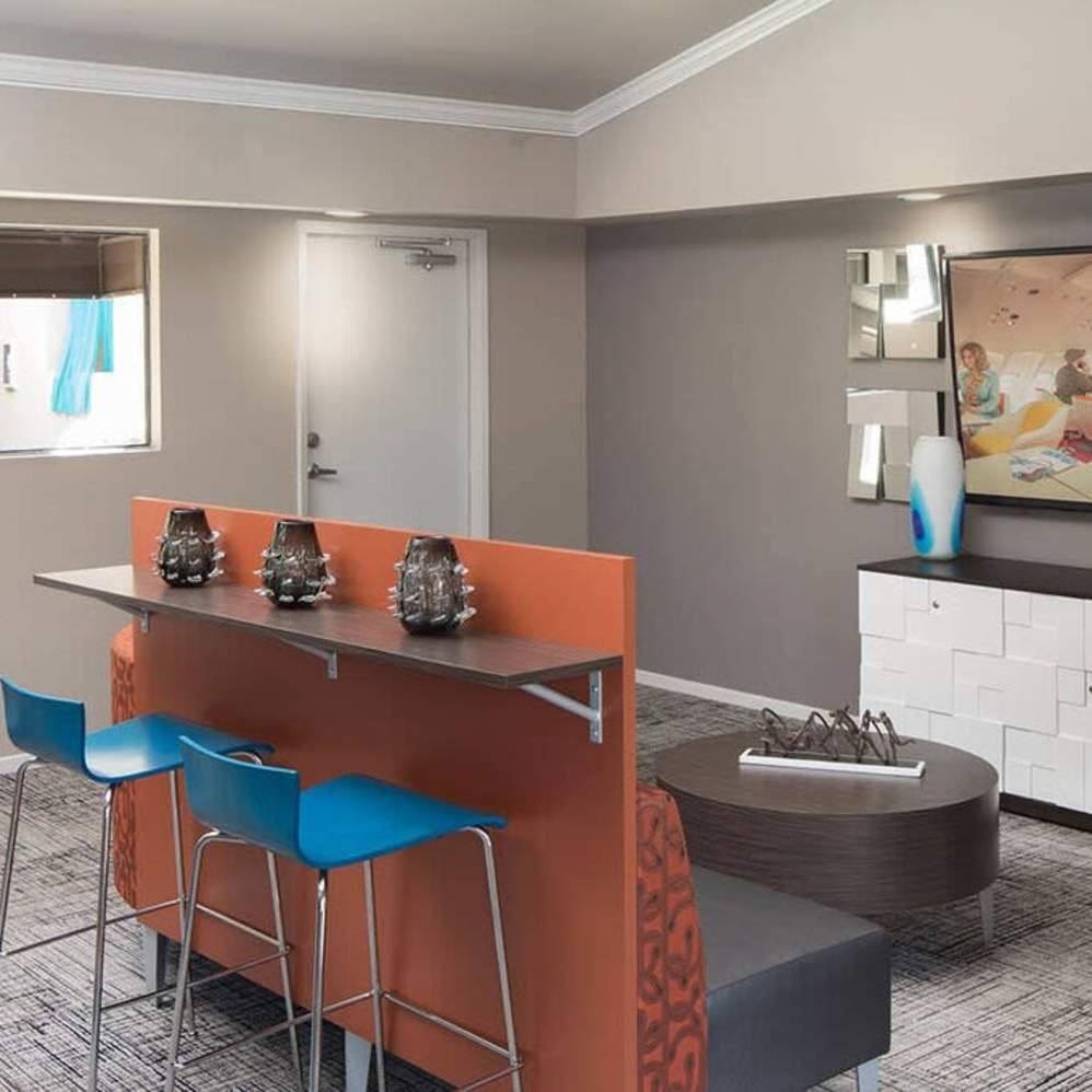 A modern kitchen with orange bar stools and a grey countertop.