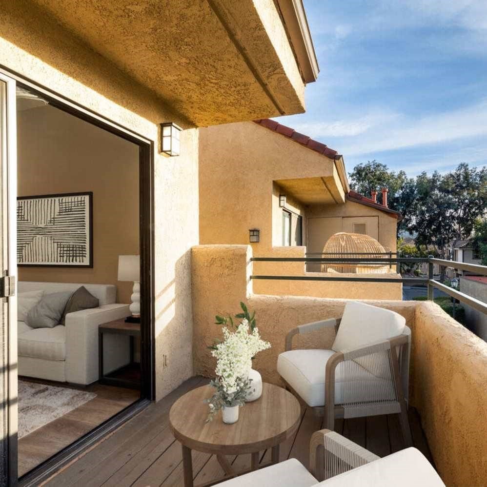 A balcony with a table and chairs overlooking a pool.