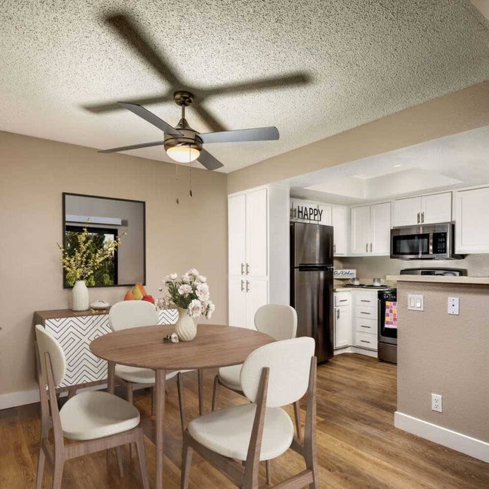 A dining room with a table and chairs and a kitchen in the background.
