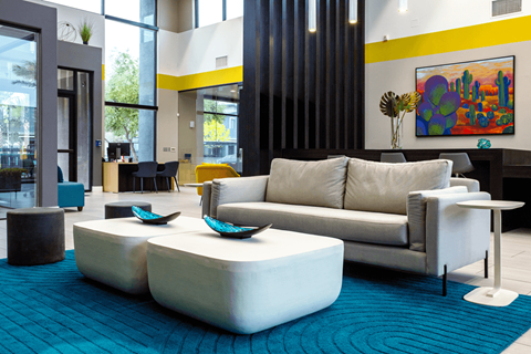 A modern living room with a white couch and a blue rug.