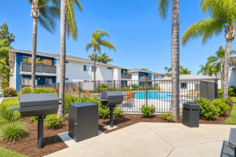 A sunny day at a residential complex with a pool and palm trees.