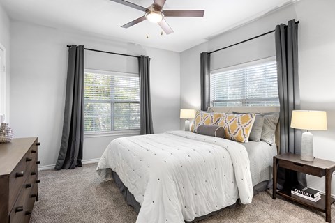 A bedroom with a large bed and a ceiling fan.