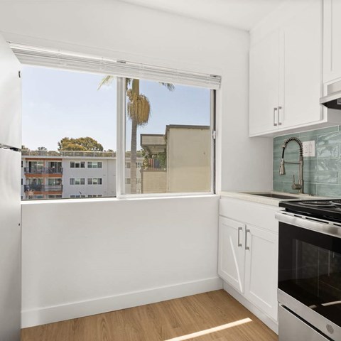 A kitchen with white cabinets and a stove top oven.