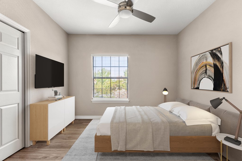 A bedroom with a bed, a television, a window, and a painting on the wall.