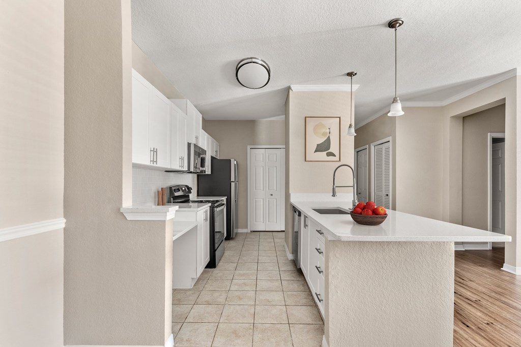 A kitchen with white cabinets and a white island with a bowl of strawberries on it.