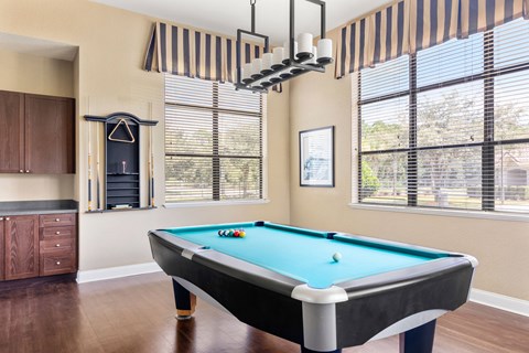 A pool table in a room with a striped awning over the window.