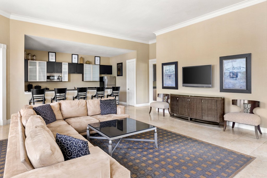 A living room with a tan couch and a glass coffee table.