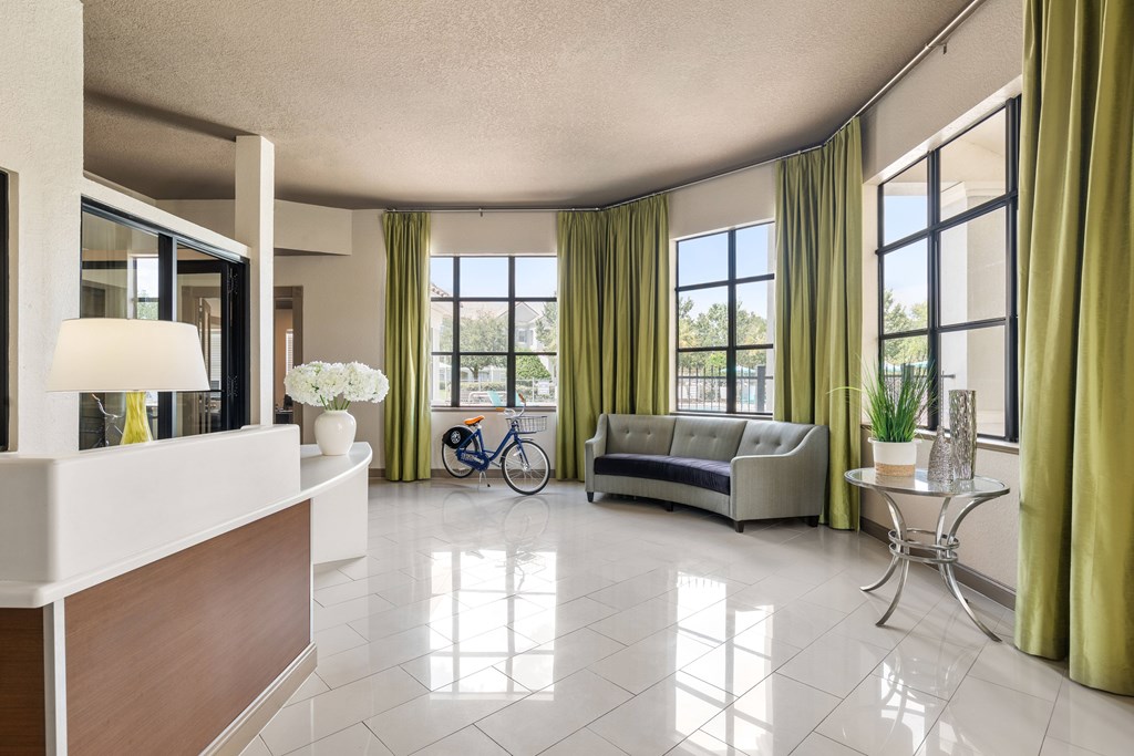 A well-lit, spacious living room with a white reception desk and a bicycle in the background.