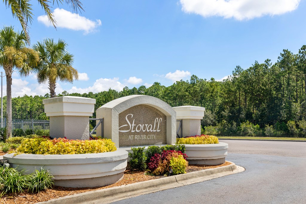 A sign that says Stovall at River City surrounded by plants and trees.