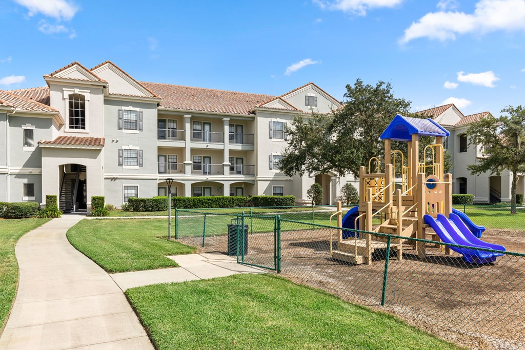 A playground with a blue slide is in front of a building.