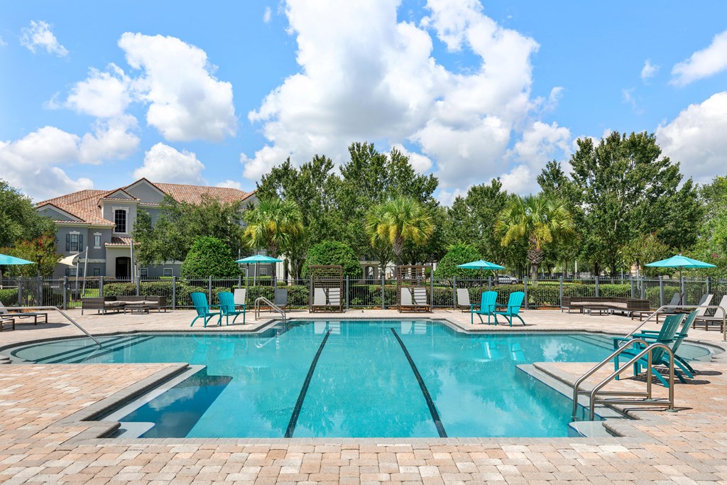 A large swimming pool surrounded by blue lounge chairs and umbrellas.