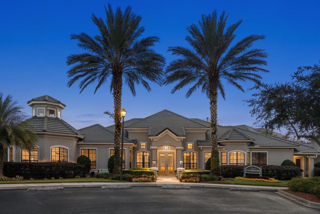A large house with a tower and palm trees in front.