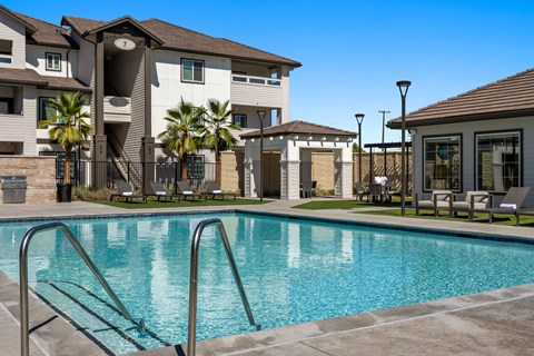 A swimming pool in front of a building with palm trees.