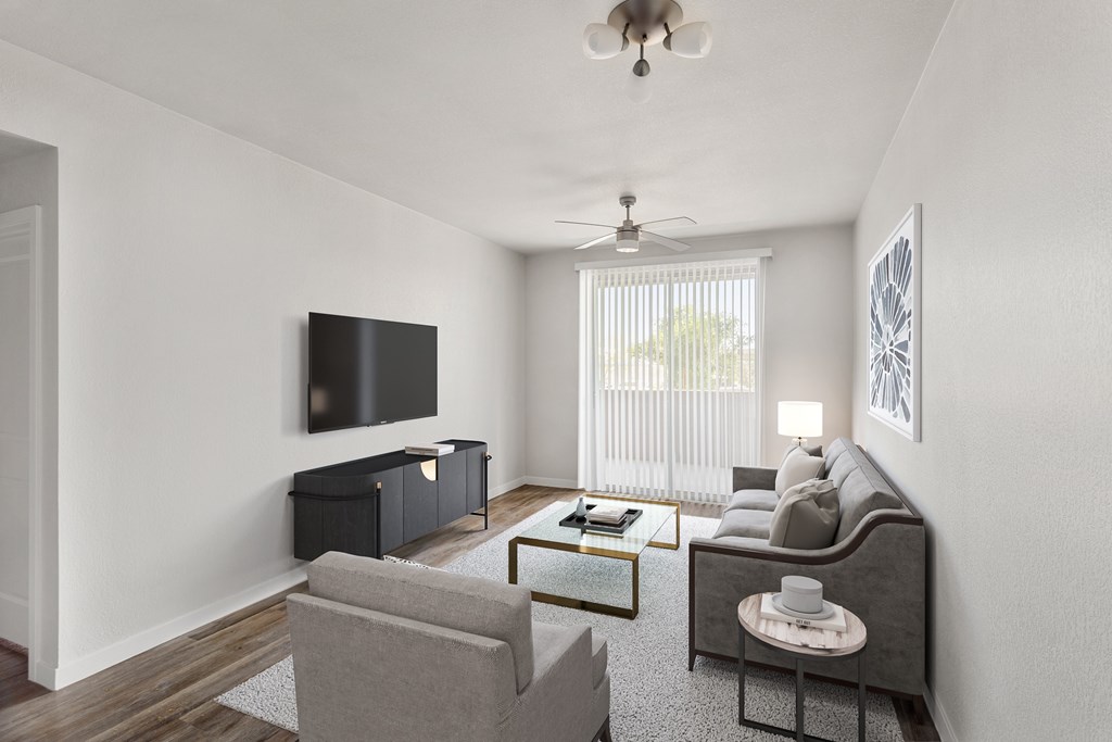 A living room with a grey couch, a coffee table, and a flat screen TV mounted on the wall.