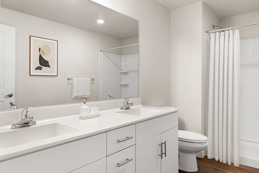 A white bathroom with a toilet, sink, and mirror.