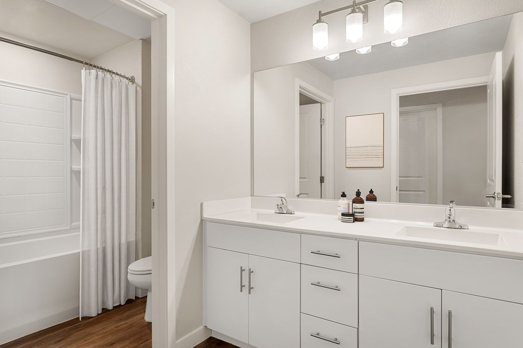 A white bathroom with a toilet, sink, and mirror.