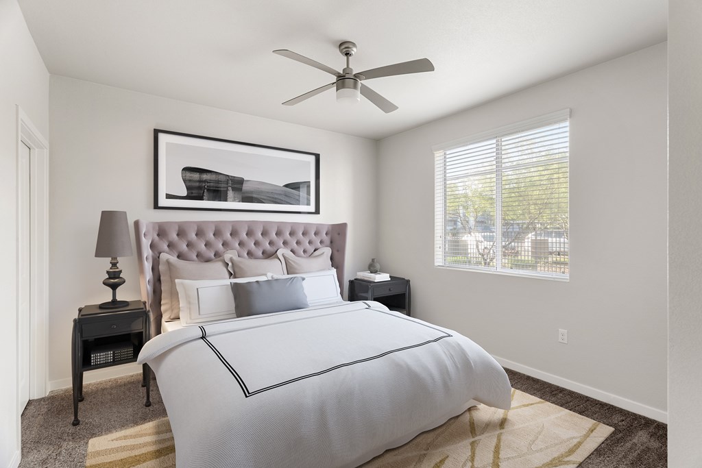 A bedroom with a large bed and a ceiling fan.