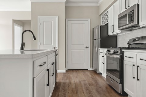 A kitchen with white cabinets and a black fridge.