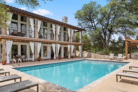 A large pool in front of a building with a balcony.
