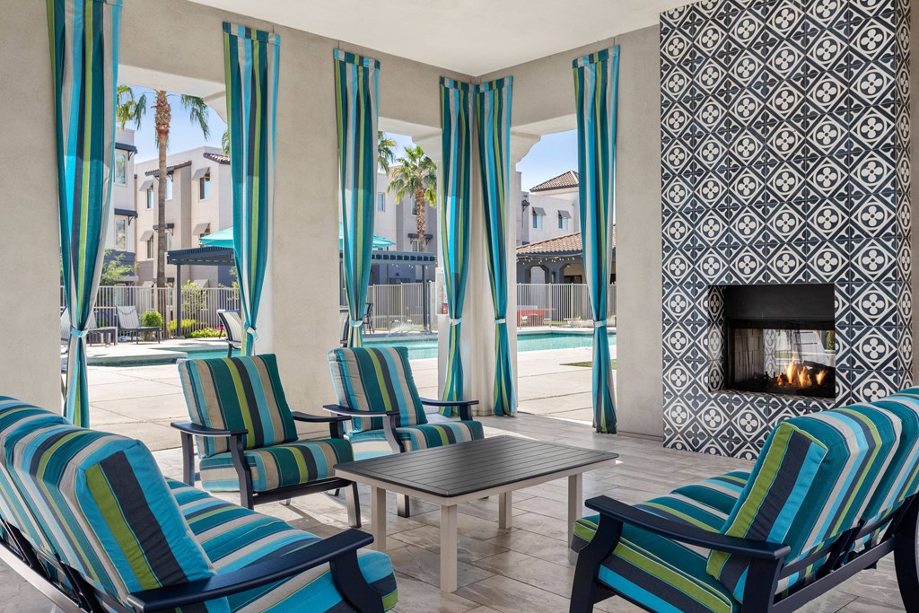 A patio with blue and green striped chairs and a fireplace.