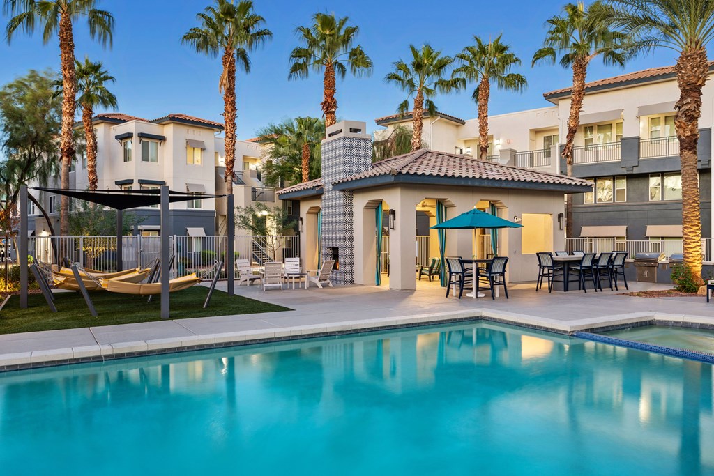 A swimming pool surrounded by palm trees and a building in the background.