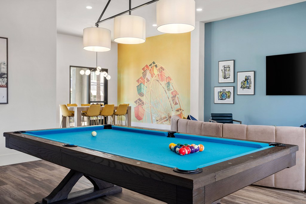 A pool table with a blue cloth and a white ball in the middle.