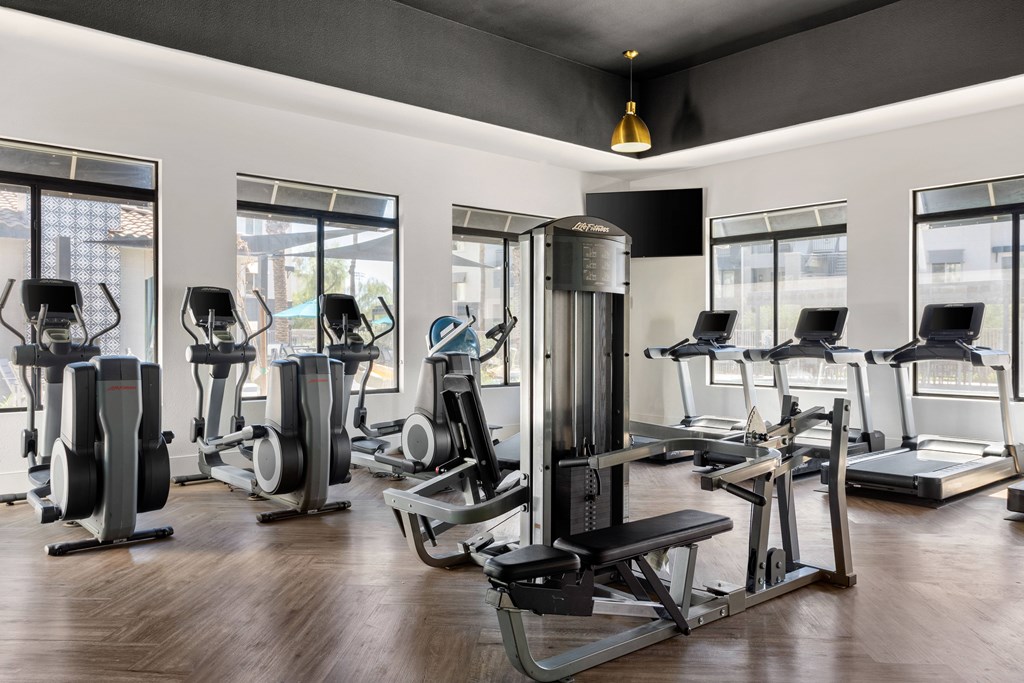 A gym with a variety of exercise equipment including treadmills, stationary bikes, and weight machines.