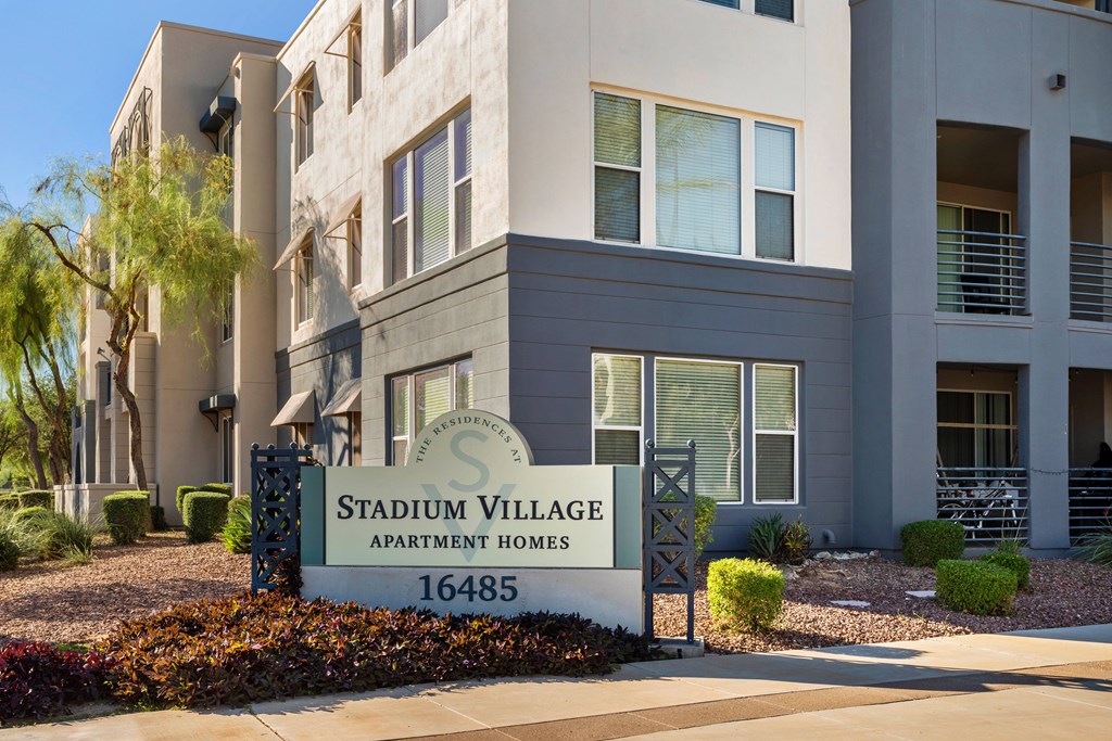 A sign for Stadium Village Apartment Homes stands in front of a building.