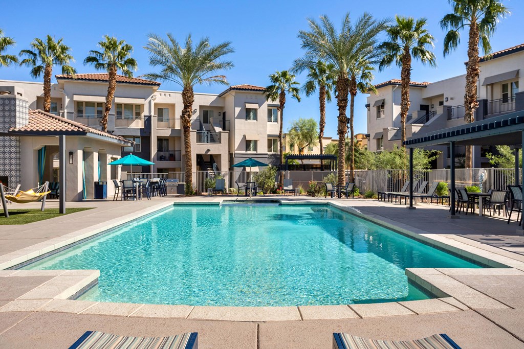 A large swimming pool surrounded by palm trees and apartment buildings.