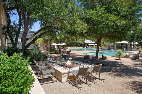 A backyard with a table and chairs and a pool.