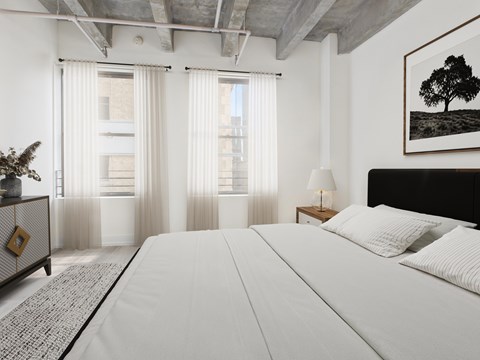A bedroom with a large bed, a nightstand with a lamp, and a framed picture of a tree on the wall.