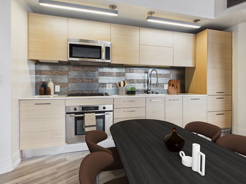 A modern kitchen with a black table and brown chairs.