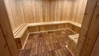 A wooden sauna with a bench and a tiled floor.