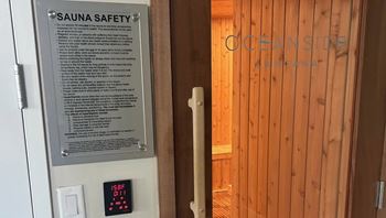 A sign for Sauna Safety is on the left and a wooden door on the right.