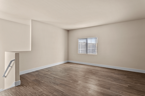 Empty room with wooden floor and a window with blinds.