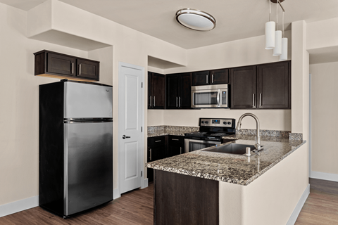 A kitchen with a black refrigerator and brown cabinets.