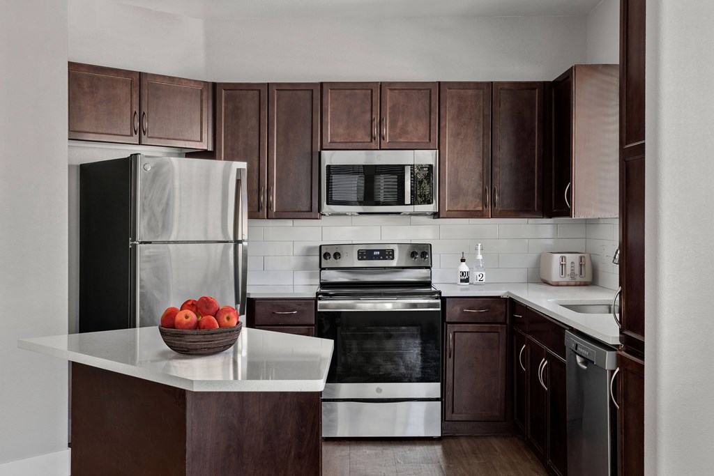 A kitchen with brown cabinets and a black refrigerator.