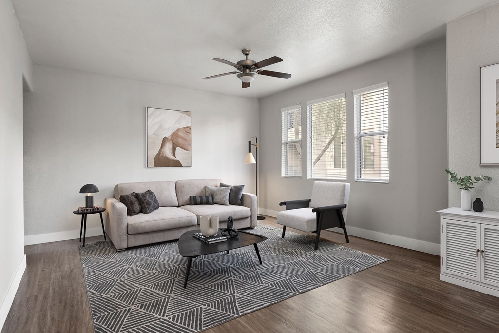 A living room with a grey couch, a coffee table, and a ceiling fan.
